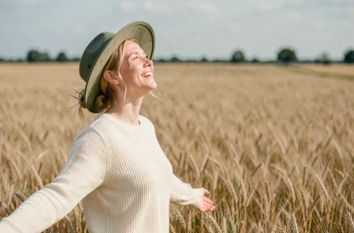 Jeune femme épanouie dans un champ de blé doré, exprimant une joie authentique et une personnalité solaire